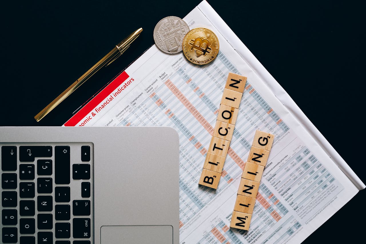 hero-01 Top view of a laptop, Bitcoin coins, and financial indicators symbolizing Bitcoin mining and investment.